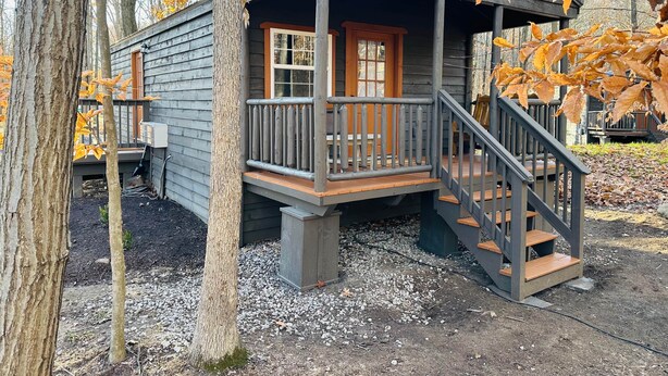 A wooden cabin with a porch and a staircase. - Hidden Oaks | The Cottage | Unit 1 (Birch Run Township)