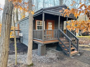 A wooden cabin with a porch and a staircase.