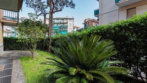 A lush garden with a large palm tree, a small tree with yellow fruits, and a well-maintained hedge. - Relax Apartment with Parking by Wonderful Italy (Santa Margherita Ligure)