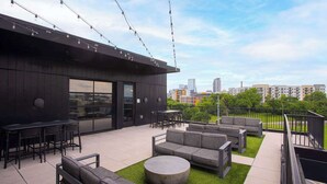 Um pátio externo com assentos, área de bar e vista para o horizonte da cidade.