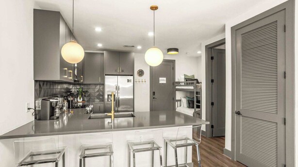 Uma cozinha moderna com ilha central, banquetas e iluminação pendente.