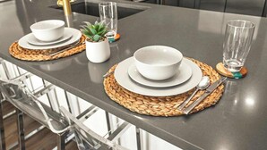 Uma cozinha moderna com eletrodomésticos de aço inoxidável, uma ilha central com um jogo americano de fibra natural e uma pequena planta em vaso.