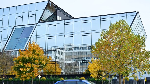 A modern building with a glass facade and a geometric design. - XENON HOSTELS UG (Dreieich)