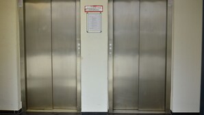 Two elevator doors with a sign above them stating "Auszug im Brandfall nicht benutzen" (Do not use the exit in case of fire). - XENON HOSTELS UG (Dreieich)