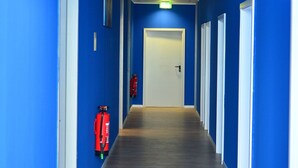 A hallway with blue walls, wooden flooring, and white doors. - XENON HOSTELS UG (Dreieich)