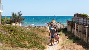 A coastal path with a sandy beach, a rocky outcrop, and a clear blue sea. - La Maison de la Plage - Solea 3 Personnes (Mauguio)