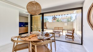 A dining area with a round table, wooden chairs, and a hanging light fixture. - La Maison de la Plage - Alma 4 Personnes (Mauguio)