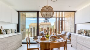 A modern kitchen with a dining area, large windows, and a view of buildings. - La Maison de la Plage - Edena 4 Personnes (Mauguio)