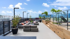 A rooftop terrace with outdoor seating, a staircase, and a view of the city. - Emunah Suites Ponta de Campina (Cabedelo)