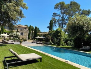 A swimming pool with lounge chairs, a stone building, and well-maintained greenery. - Villa Hautvallon (Gordes)