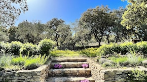 A stone staircase leading up to a garden area with stone walls and various plants. - Villa Hautvallon (Gordes)