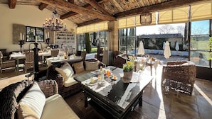 A spacious dining area with wicker furniture, a chandelier, and a view of the outdoors. - Villa Hautvallon (Gordes)