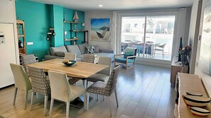 A modern living room with a dining area, a sofa, a coffee table, and a large window with a view. - Dunas Beach Penthouse (Torrox)