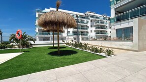 A modern building with a grassy area, a lifebuoy, and a palm tree. - Dunas Beach Penthouse (Torrox)