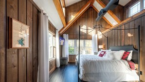 Una camera da letto con un letto grande, pareti in legno e soffitto spiovente.