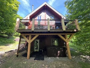 Una cabaña con balcón, jacuzzi y zona exterior cubierta.