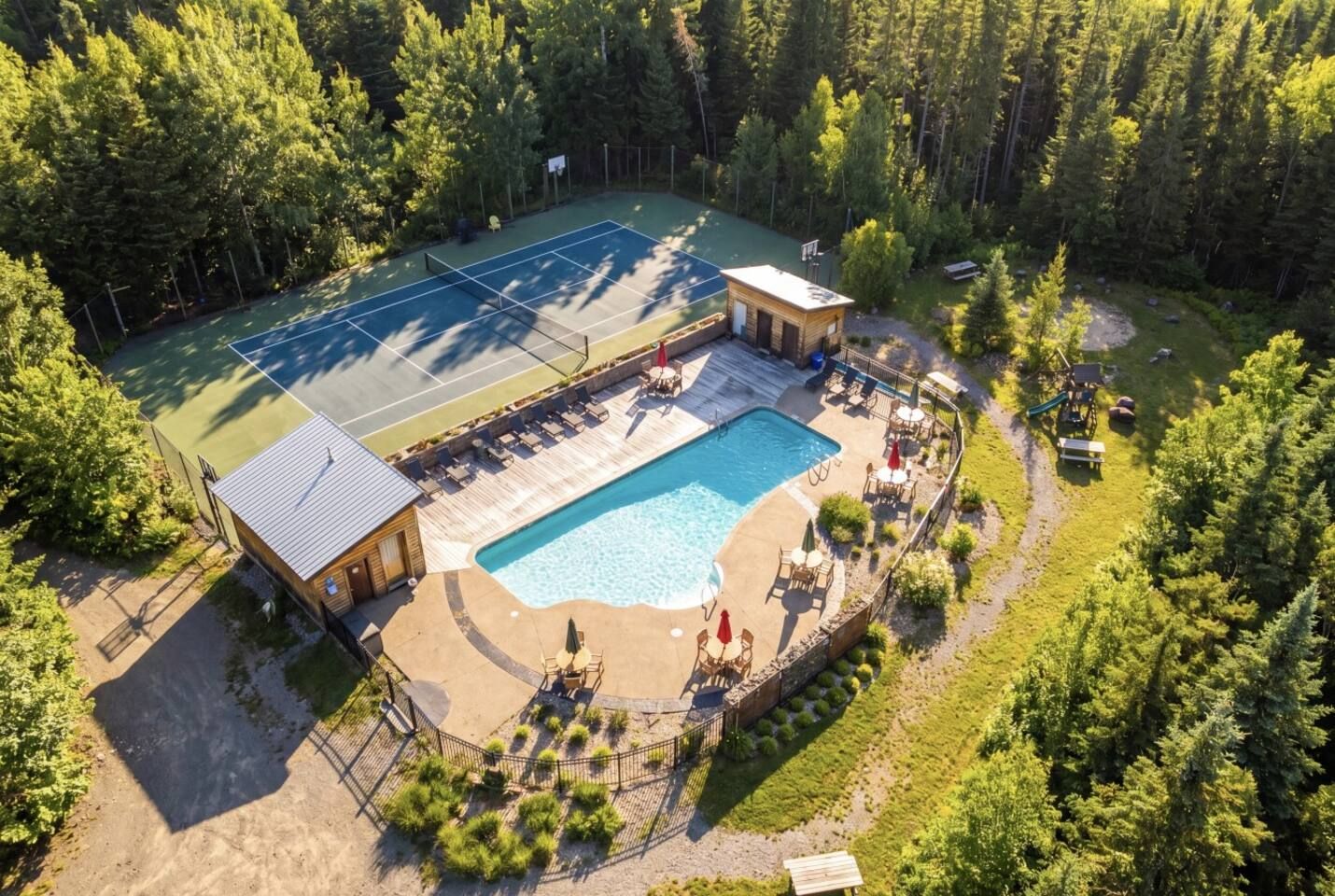Un court de tennis, une piscine et un petit bâtiment doté d’un toit.