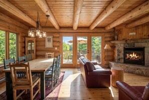 A log cabin interior with a dining area, a fireplace, and a sofa.