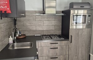Eine moderne Küche mit Gaskochfeld, Edelstahlbackofen und integriertem Mikrowellenherd.
