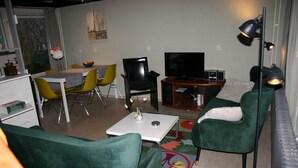 A living room with green chairs, a white table, a TV, and a small cabinet. - Bungalowpark Simpelveld - Alpha 95 (Simpelveld)
