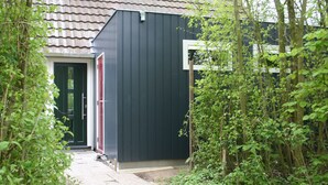 A dark-colored building with a tiled roof, a door, and a small entrance. - Bungalowpark Simpelveld - Alpha 95 (Simpelveld)
