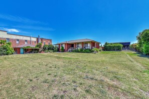 A residential area with a house featuring a front porch and a well-maintained lawn. - Helena Grand Estate Hunter Valley (Ellalong)