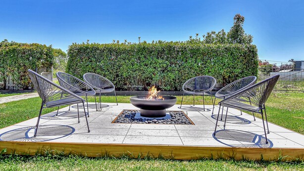 A circular outdoor seating area with a central fire feature surrounded by metal chairs. - Helena Grand Estate Hunter Valley (Ellalong)