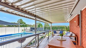 A covered patio with a pool, outdoor furniture, and a view of a backyard. - Helena Grand Estate Hunter Valley (Ellalong)