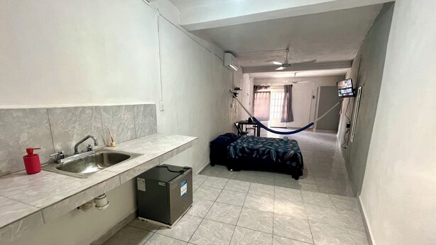 A compact hotel room with a kitchenette, a bed, and a view of the hallway. - Private rooms with climate control, fan and internet (Tulum)