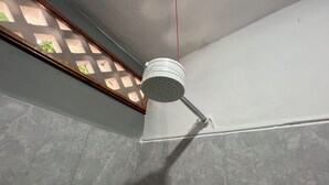 A corner of a room with a white ceiling, a white showerhead, and a window with a wooden frame and a lattice design. - Private rooms with climate control, fan and internet (Tulum)
