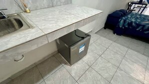 A kitchen with a sink, a countertop, and a small refrigerator. - Private rooms with climate control, fan and internet (Tulum)