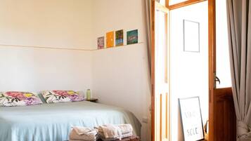 Ein Schlafzimmer mit Bett, Kissen, Koffer und einer Tür mit einem Schild.
