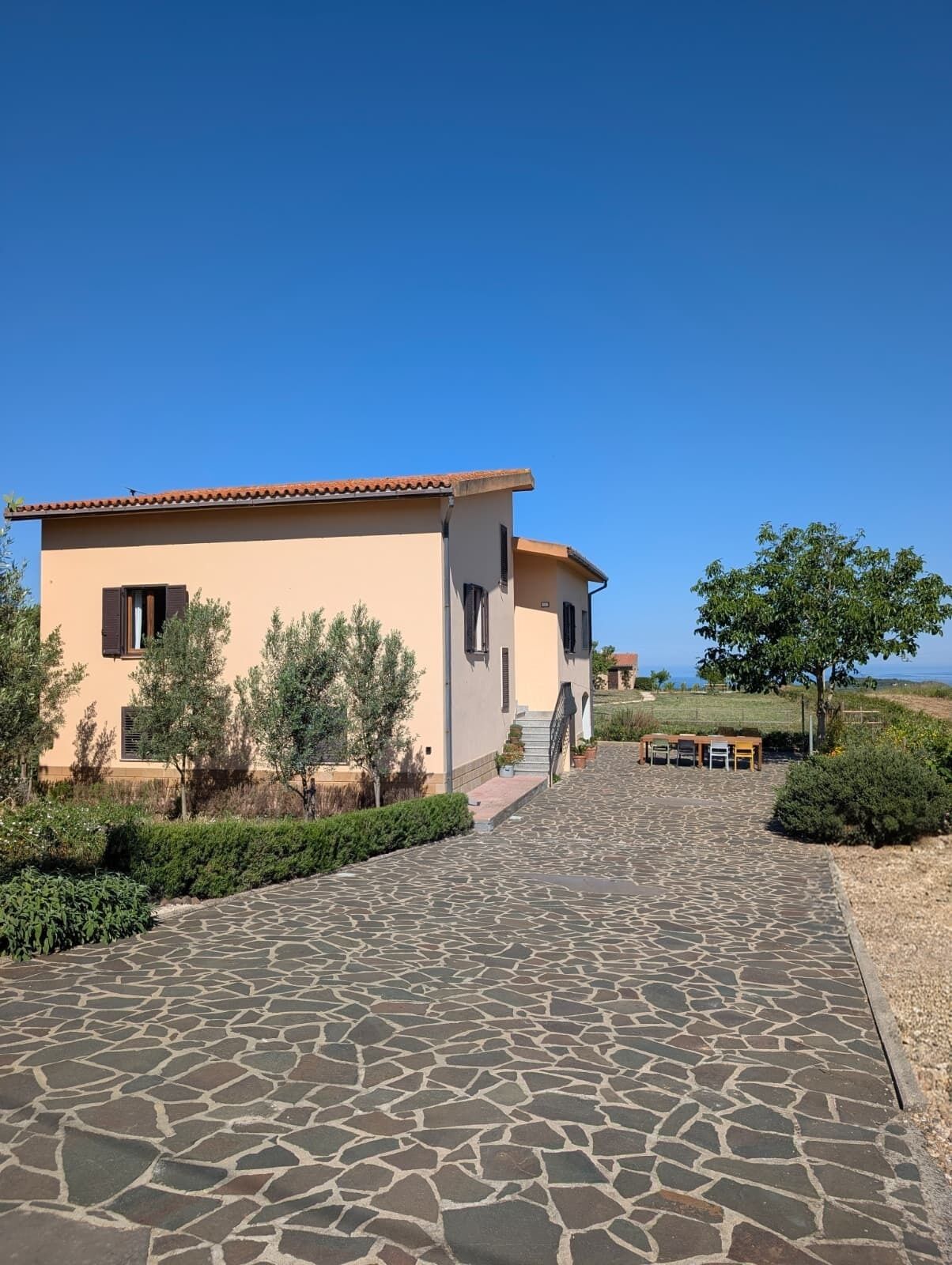 A building with a tiled roof, a stone-paved entrance, and a clear sky.