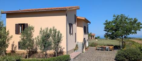 A building with a tiled roof, a stone-paved entrance, and a clear sky.