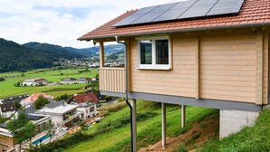 A house with a balcony, solar panels, and a view of a valley. - Holiday Home 'Panoramahisli 3' with Mountain View, Balcony and Air Conditioning (Fischerbach)