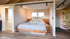 A wooden-paneled bedroom with a bed, a window, and a door. - Holiday Home 'Panoramahisli 3' with Mountain View, Balcony and Air Conditioning (Fischerbach)