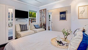 Une chambre moderne avec un grand lit, deux canapés, une télévision et des œuvres d’art accrochées aux murs.