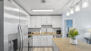 A modern kitchen with white cabinets, stainless steel appliances, and a granite countertop. - Bright & Stylish Condo Near Everything! (Panama City Beach)