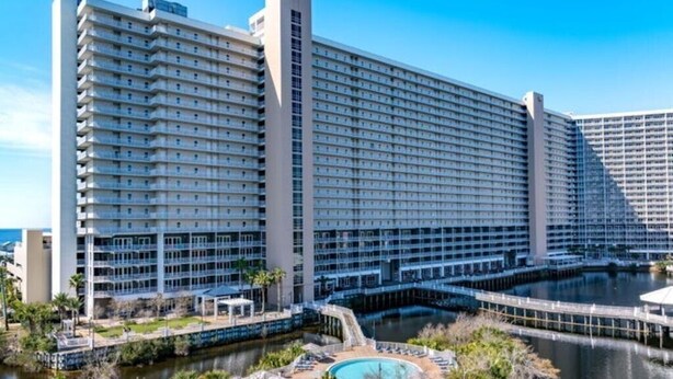 A large hotel with multiple floors, a pool area, and a waterfront view. - Bright & Stylish Condo Near Everything! (Panama City Beach)