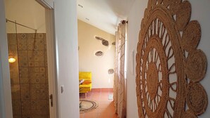 Un couloir doté d’un sol carrelé à motifs, d’un canapé jaune et d’un élément décoratif mural.
