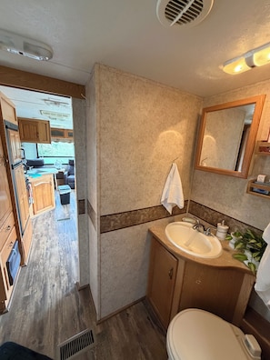 A compact RV bathroom with a sink, mirror, and toilet. - Rv with 1 Bedrooms, and sofa bed Full Kitchen, Dining Area & Modern Bathroom” (Pikeville)
