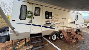 A camper with a covered entrance, a window, a door with a wreath, and a 'Life is better when you camp' sign. - Rv with 1 Bedrooms, and sofa bed Full Kitchen, Dining Area & Modern Bathroom” (Pikeville)
