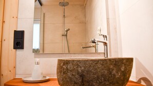 A bathroom with a stone sink, a handheld showerhead, and a mirror. - Apartment 'Panoramahisli 4' with Mountain View, Balcony and Air Conditioning (Fischerbach)