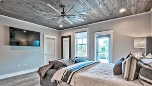 A modern bedroom with a large bed, a ceiling fan, and a TV mounted on the wall. - King's Castle | Luxury Beach Escape | Huge Private Pool/Spa | 6-Seater Golf Cart (Destin)