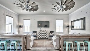 A room with a wooden floor, white walls, a large mirror, and a ceiling fan. - King's Castle | Luxury Beach Escape | Huge Private Pool/Spa | 6-Seater Golf Cart (Destin)