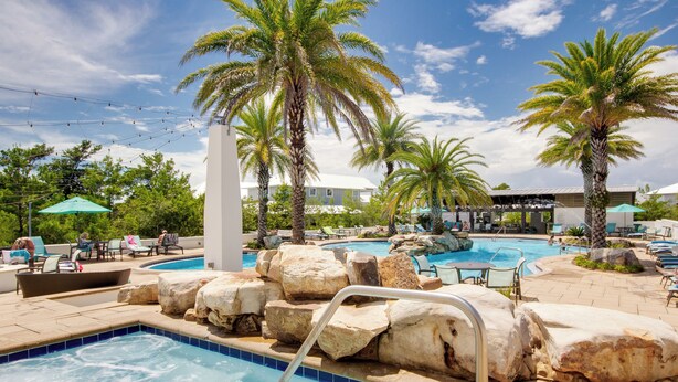 Ein Poolbereich mit mehreren Pools, Liegestühlen und Palmen.