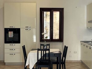 Une cuisine compacte comprenant une table à manger, des chaises, une fenêtre et des appareils électroménagers intégrés.