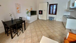 A compact living space with a dining area, kitchenette, and a small window. - Arte 36 (Bosa)