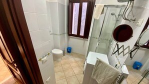A bathroom with a toilet, bidet, and a glass shower enclosure. - Arte 36 (Bosa)