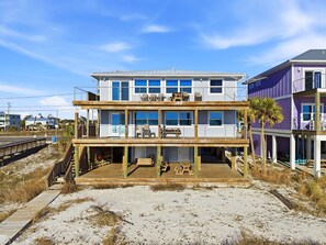 A two-story beachfront house with a wooden deck, outdoor seating, and a view of the ocean. - Stunning Beachfront Mexico Beach| 6 BR, Sleeps 18 (Mexico Beach)